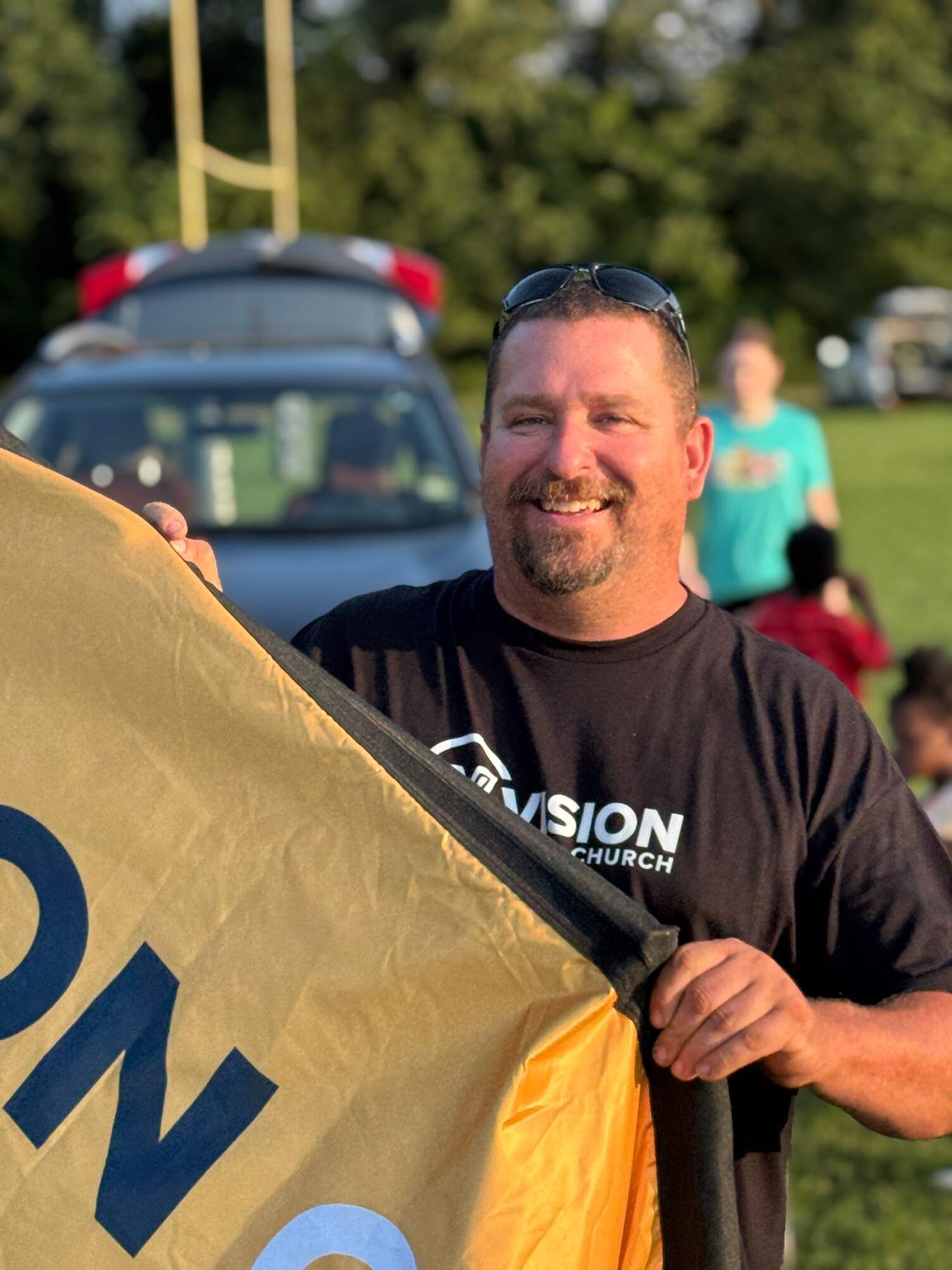 A man wearing a shirt that says Vision Church, while holding a sign.