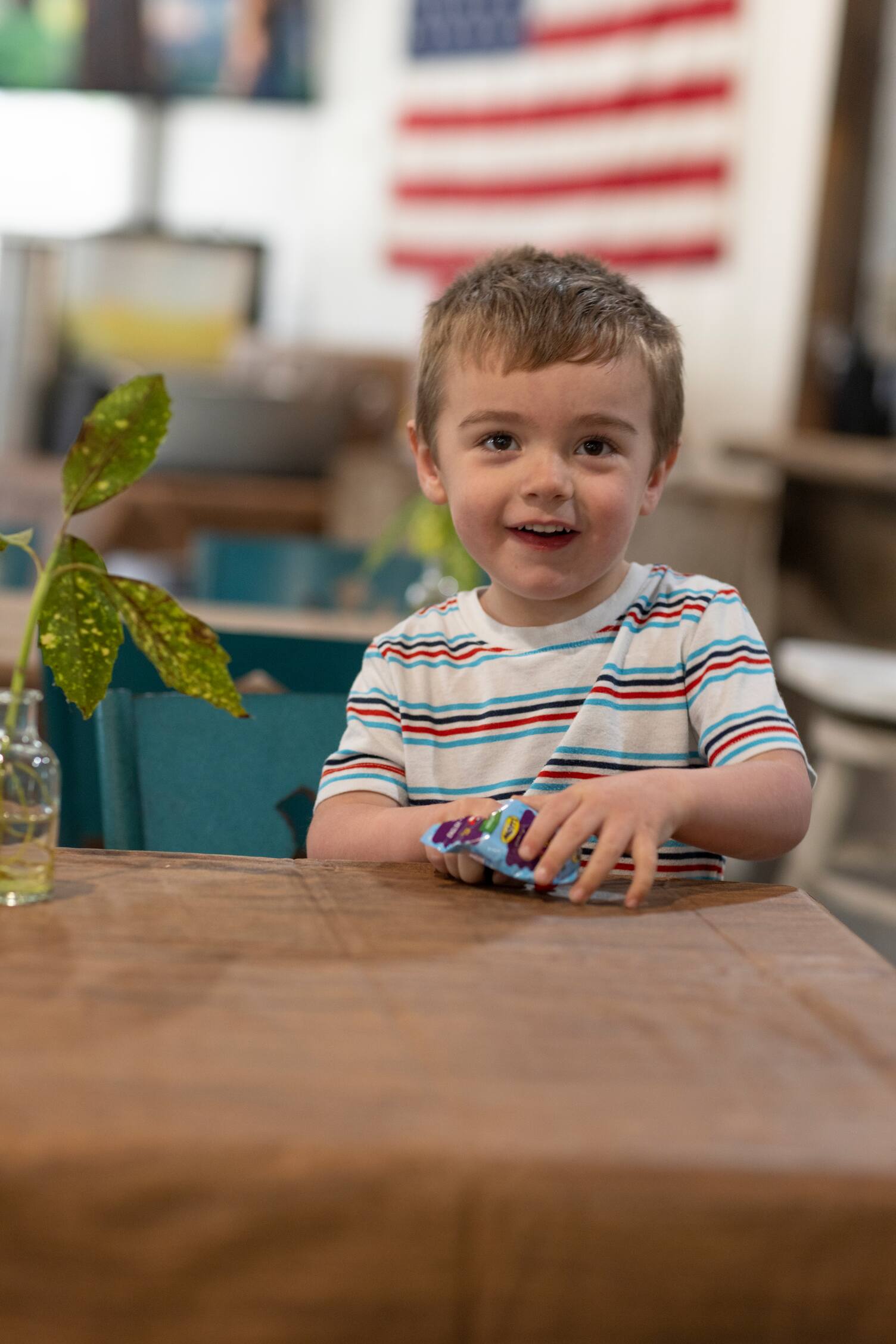 A boy sitting at a table eating fruit snacks