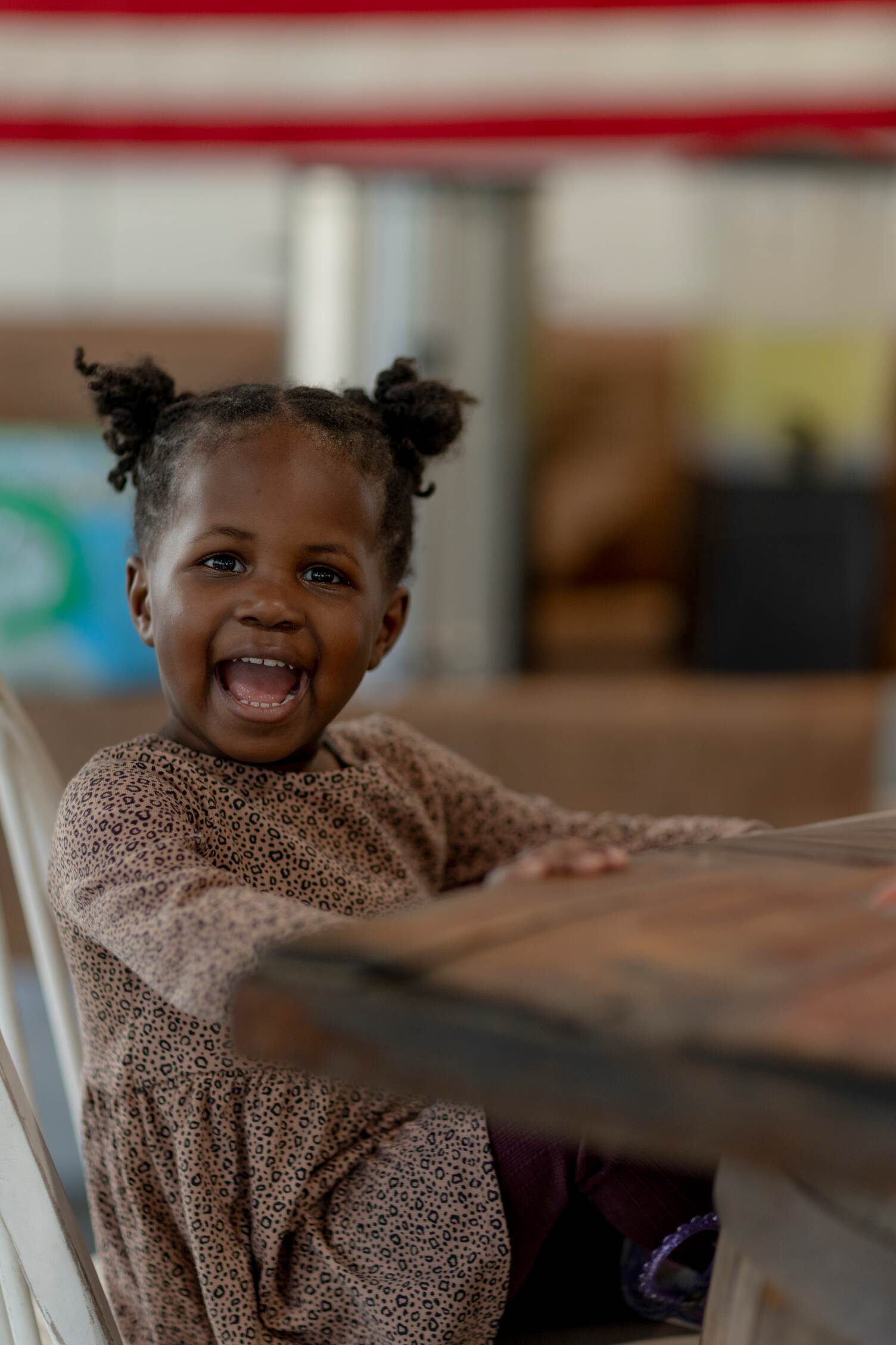 A toddler girl sitting at a table smiling