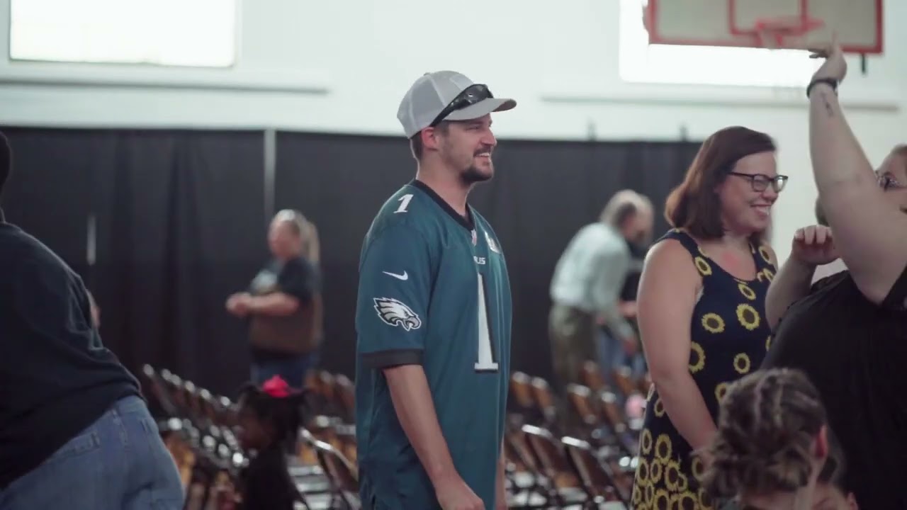A guy wearing a jersey talking to a group of people