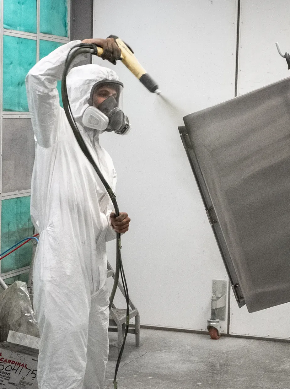 A worker painting in full protective gear a respirator and coveralls.