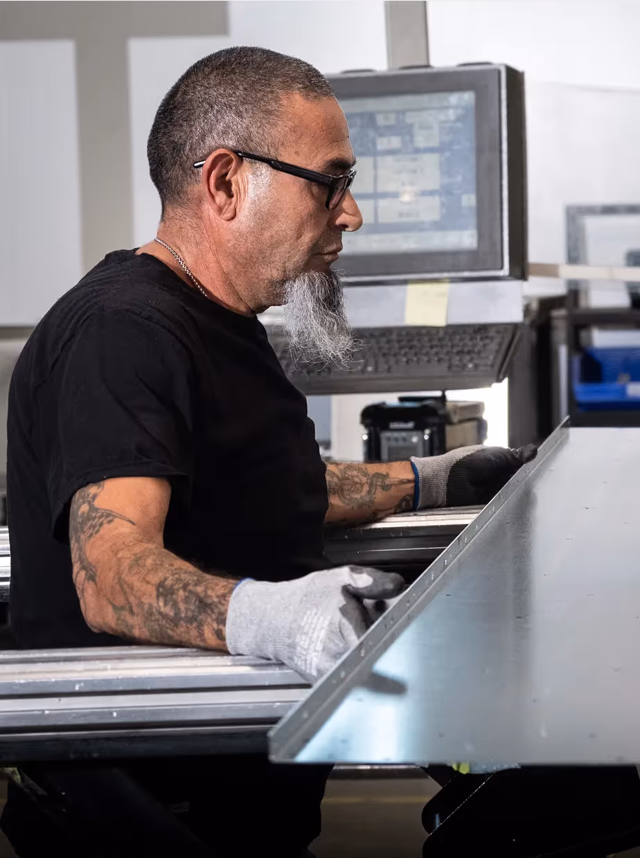 Technician handling sheet metal for GPU data center fabrication.