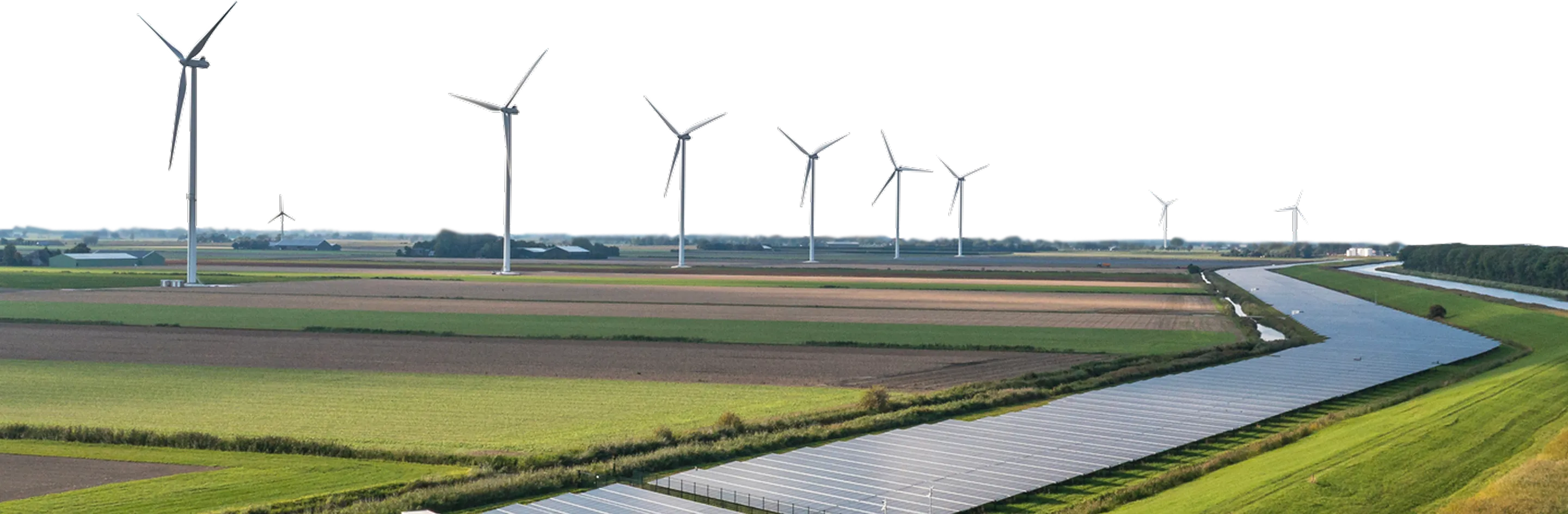 A rural landscape showing hybrid generation, a large array of solar panels alongside a canal and a line of wind turbines.
