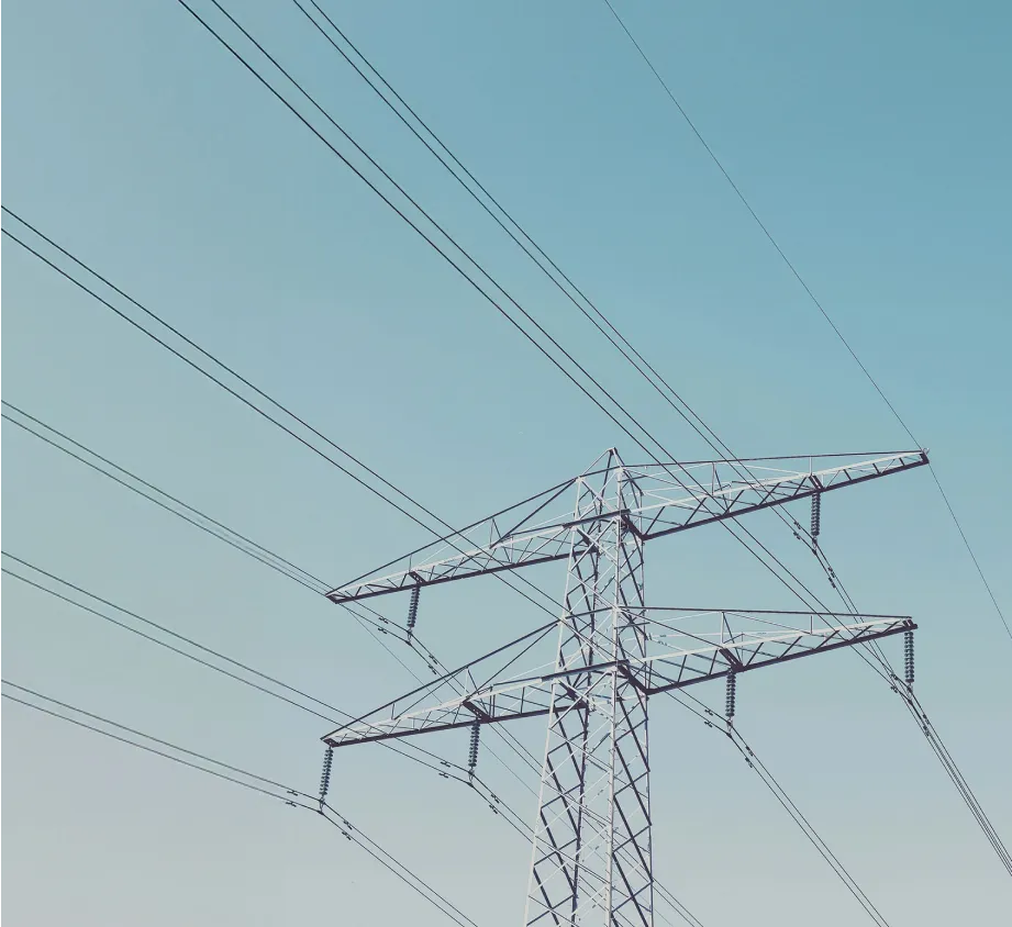 A steel lattice electrical transmission tower, a vital component of the electrical grid, stands against a clear sky.