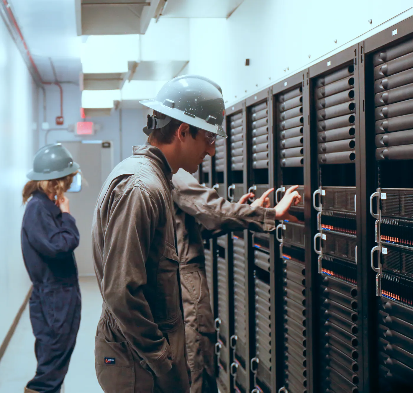 Crusoe employees in protective gear managing GPU servers inside a data center.