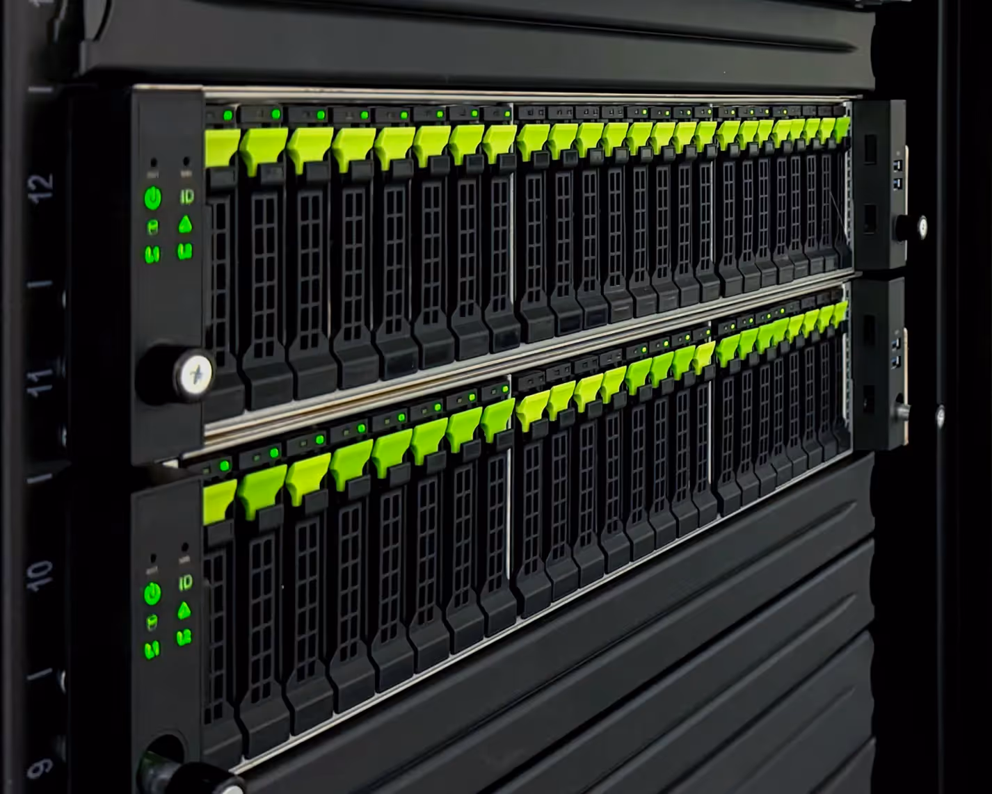 Close-up of two server racks with illuminated green status indicator lights and bright green levers on hard drive bays.