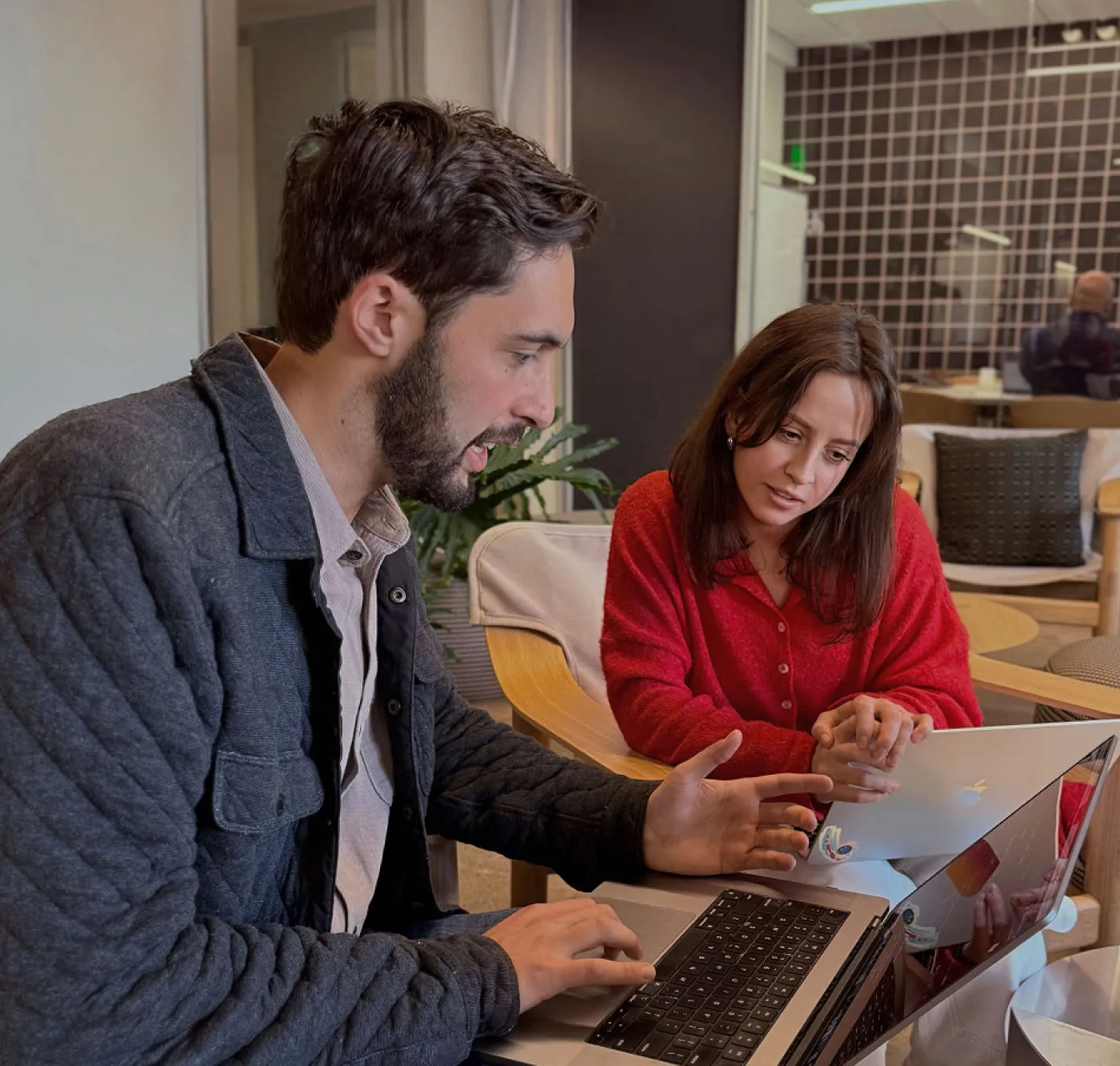 Image of 2 people working together in an office environment with their laptops.