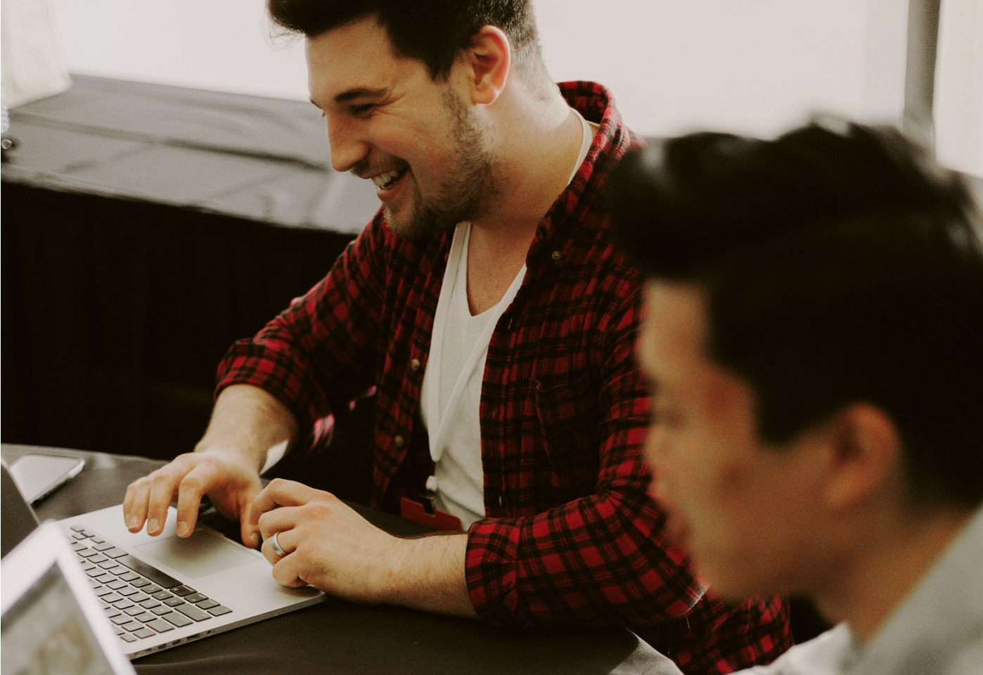 Image of 2 people working side by side looking at a laptop