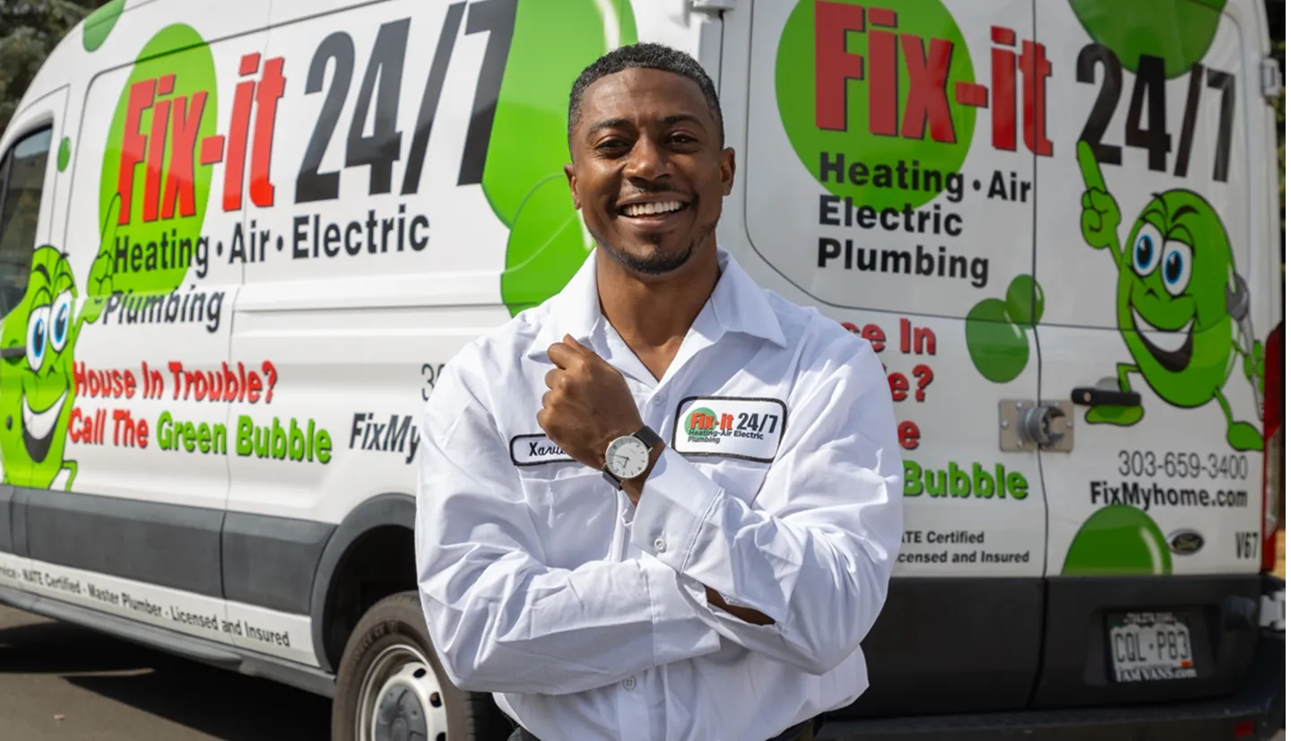 A Fix-it technician stands smiling in front of a service van.