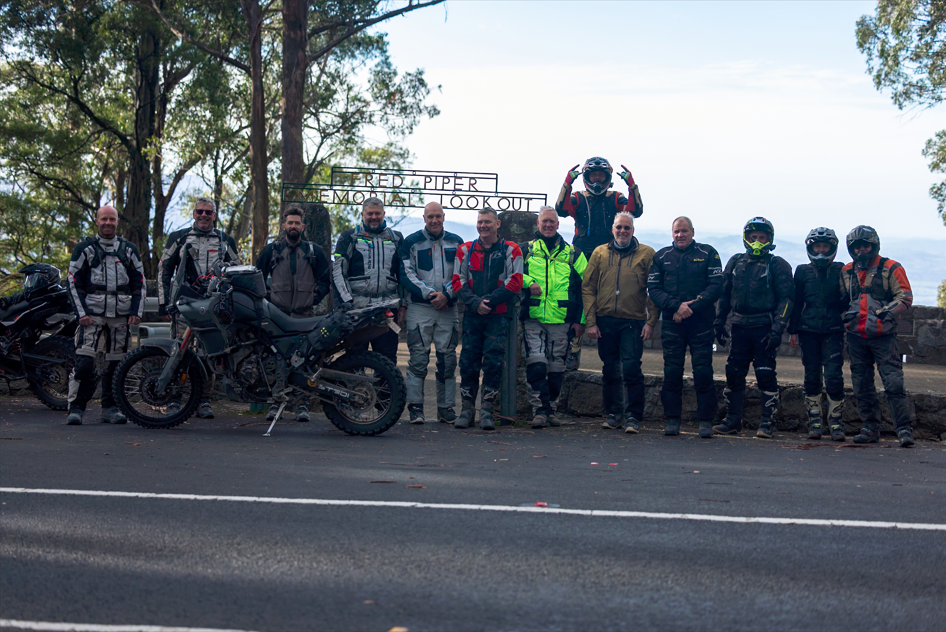 A group of motorcycle riders standing on the side of the road