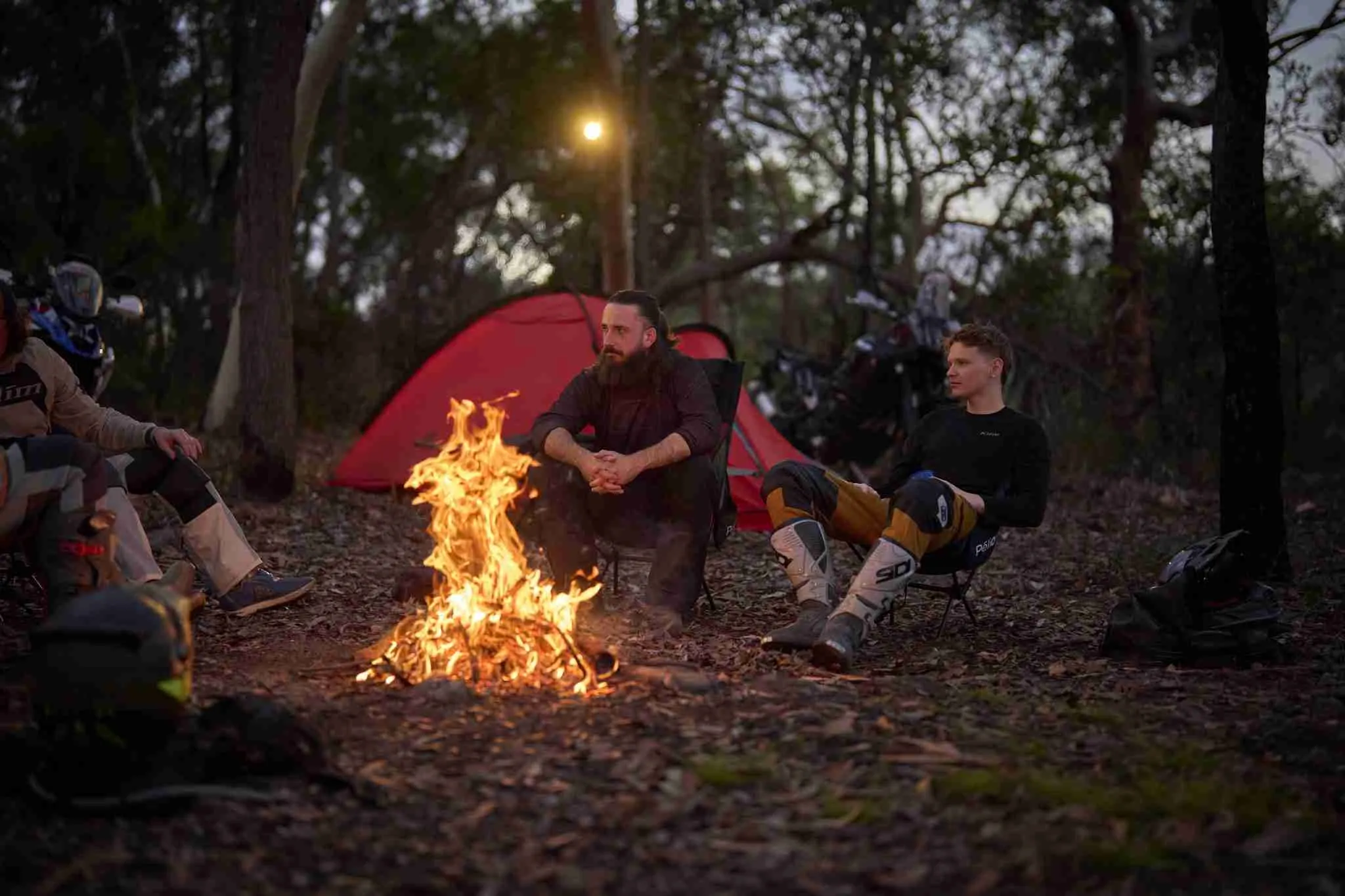 Four motorcycle riding friends chatting around a campfire