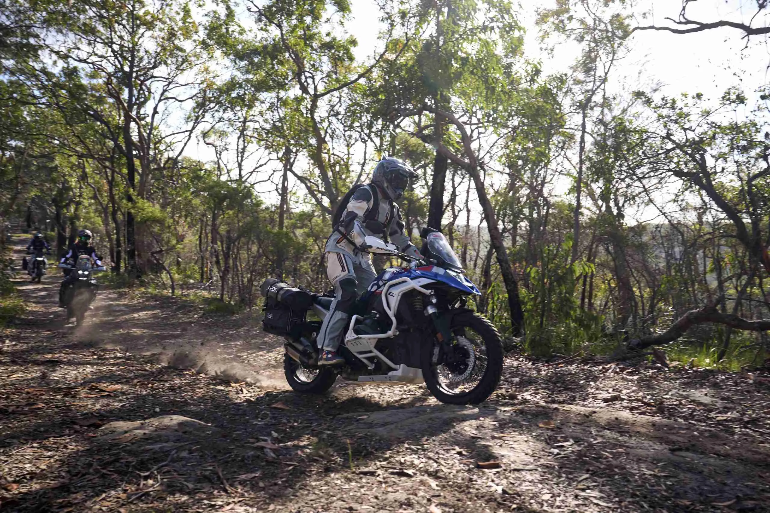 A motorcycle rider riding a BMW R1300GS in the bush