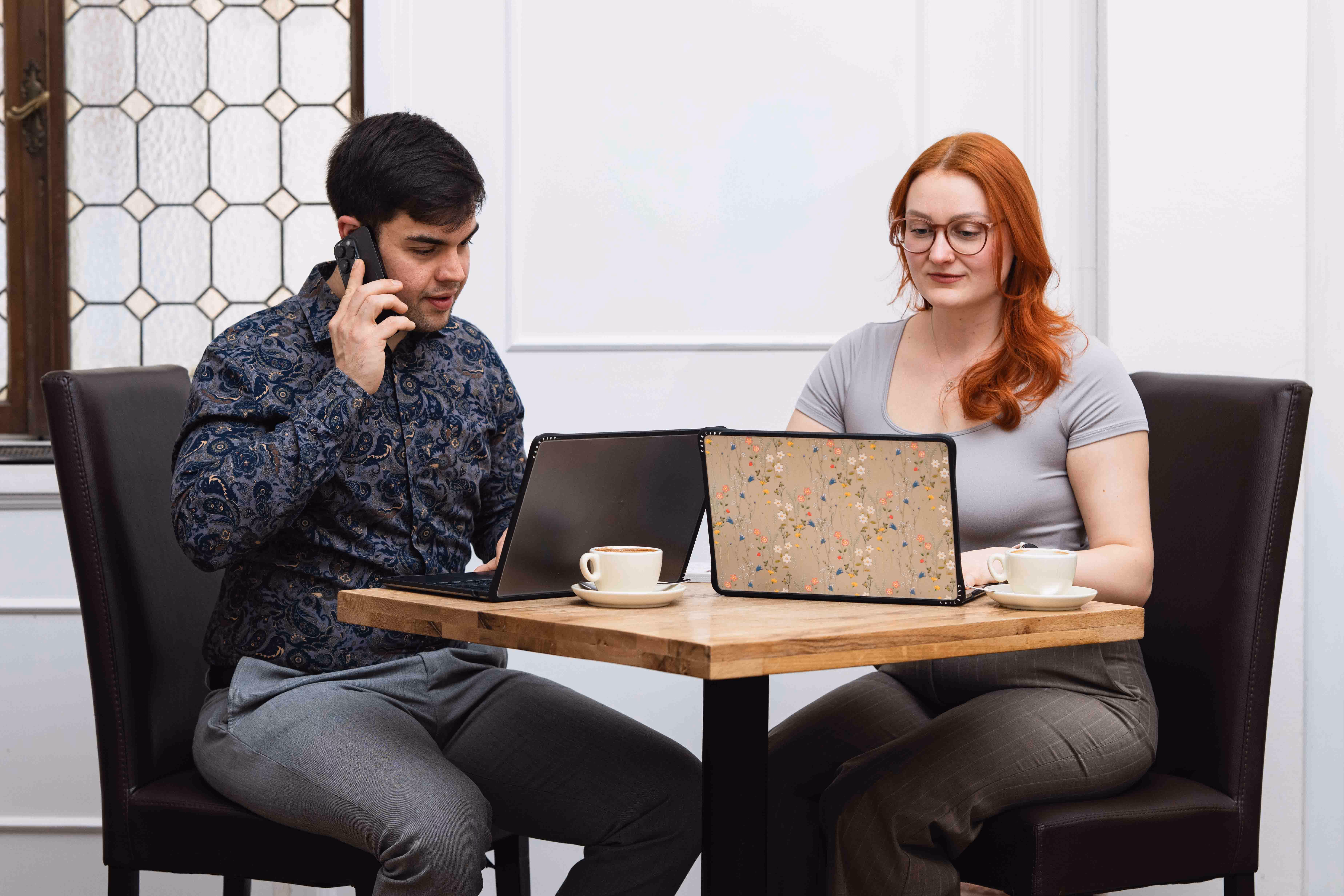 Bernhard telefoniert mit einem Kunden, Jennifer arbeitet parallel am Laptop