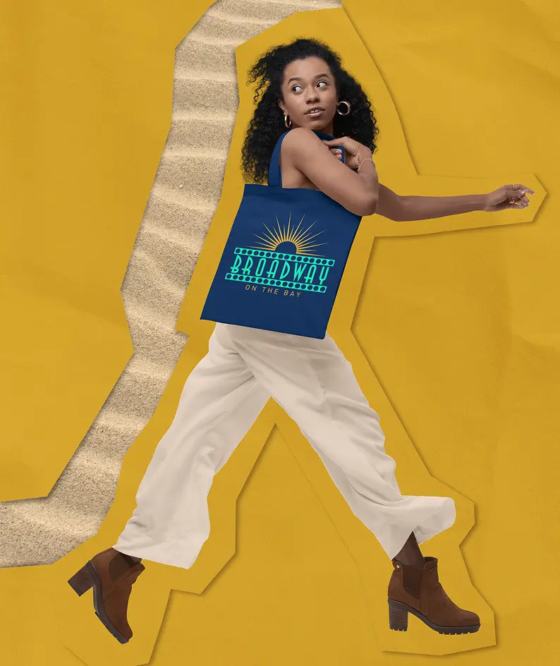 Performer in Broadway on the Bay merchandise posing against a bold yellow background with graphic stage curtain accents