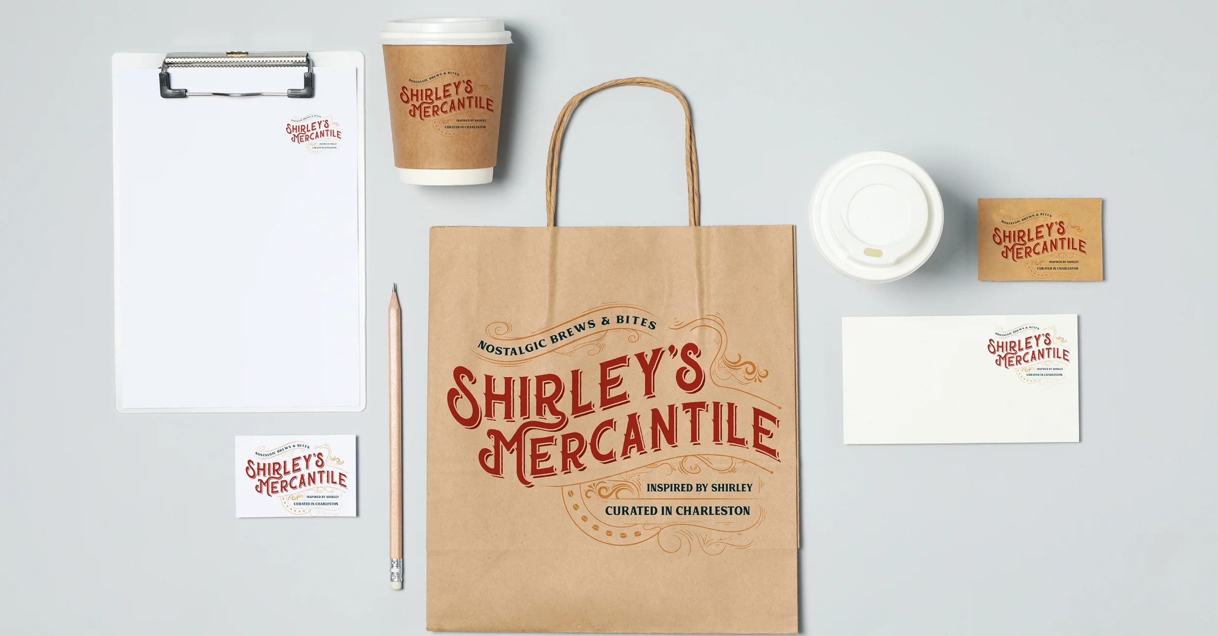 Flat lay of Shirley’s Mercantile brand assets including coffee cup, shopping bag, clipboard, and sticker packaging