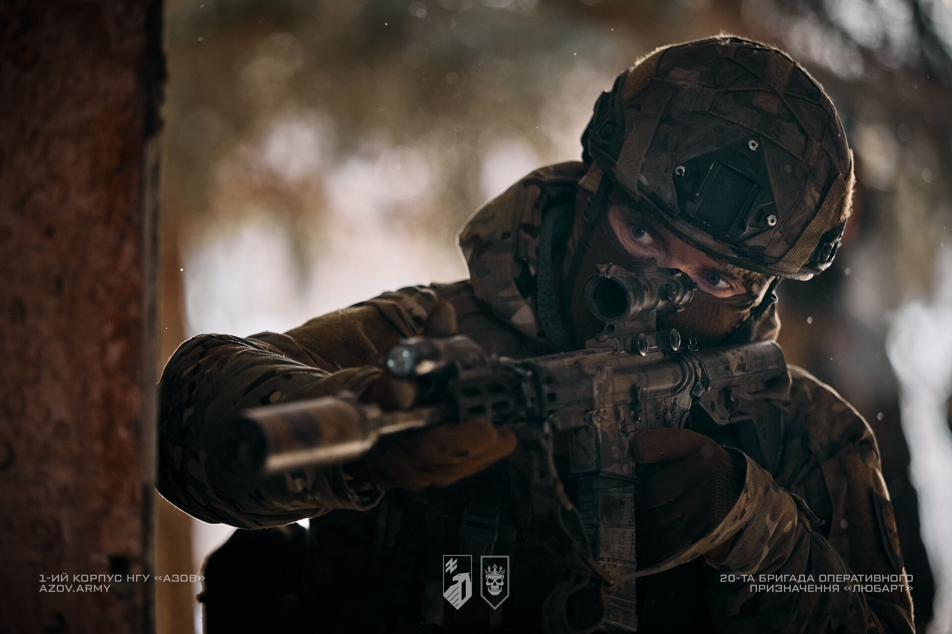 Розвідник 20 бригади «Любарт» з гвинтівкою визирає з укриття в приміщенні