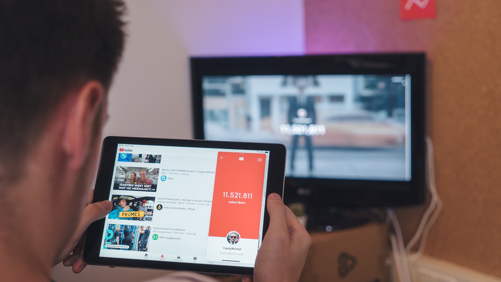 Spectateur consultant une tablette devant sa télévision