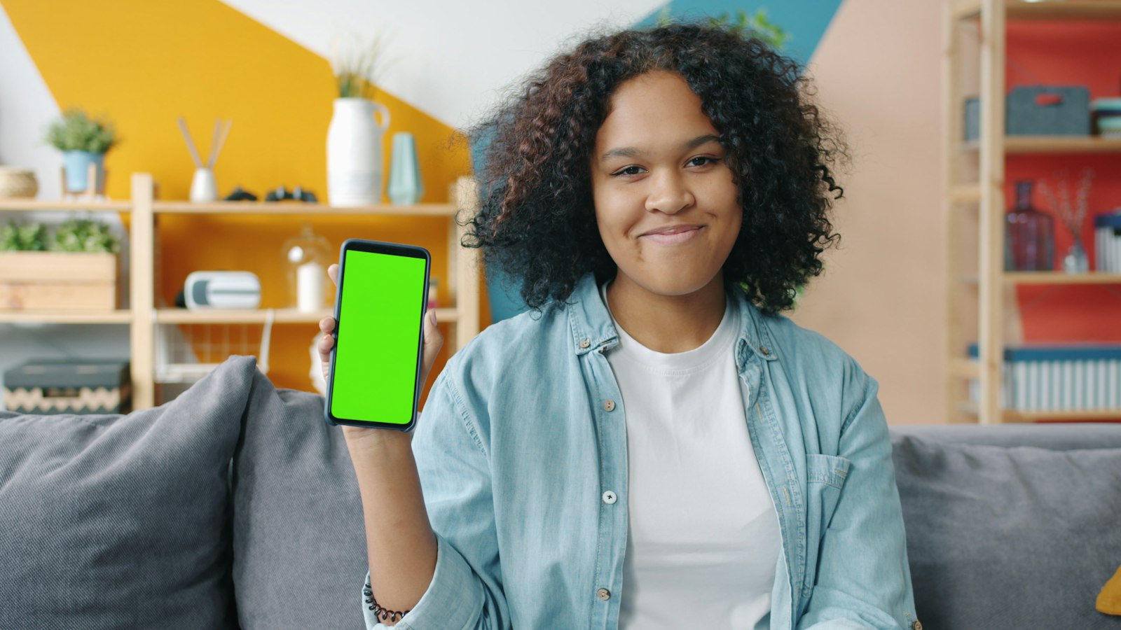 Jeune femme tenant un smartphone devant un fond vert