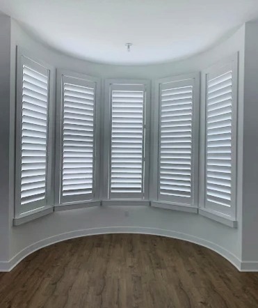 Sample custom wood shutters in living room with bay window shape
