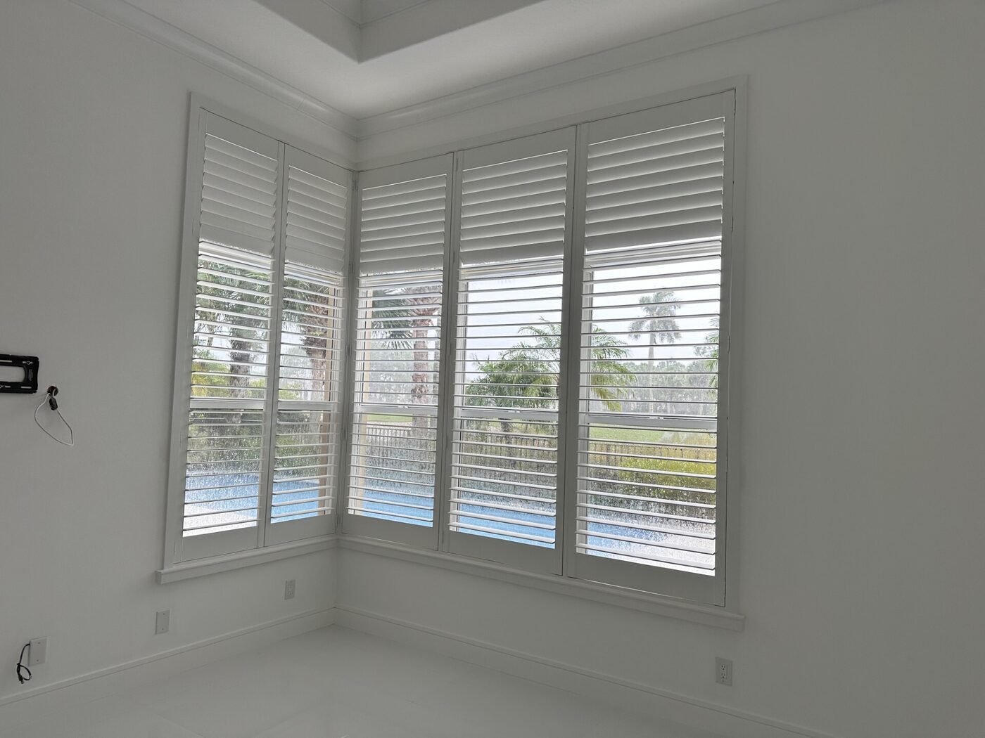 Real-wood plantation shutters on a bay window overlooking a pool in a Port St. Lucie home