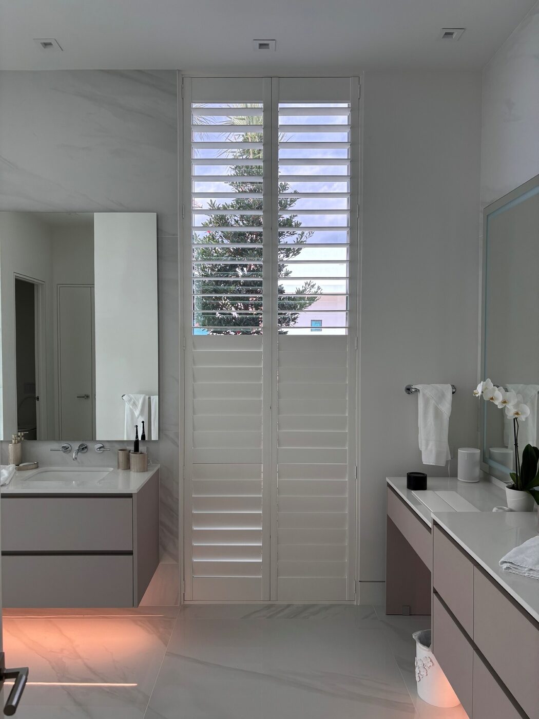 Custom real-wood plantation shutters on a tall master bathroom window in a Port St. Lucie home for privacy and light control