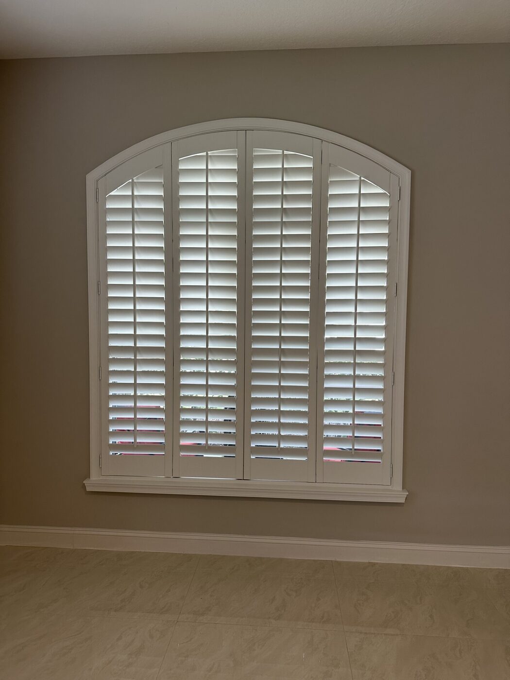 Custom real-wood plantation shutters on an arched specialty window in a Hobe Sound, FL estate home