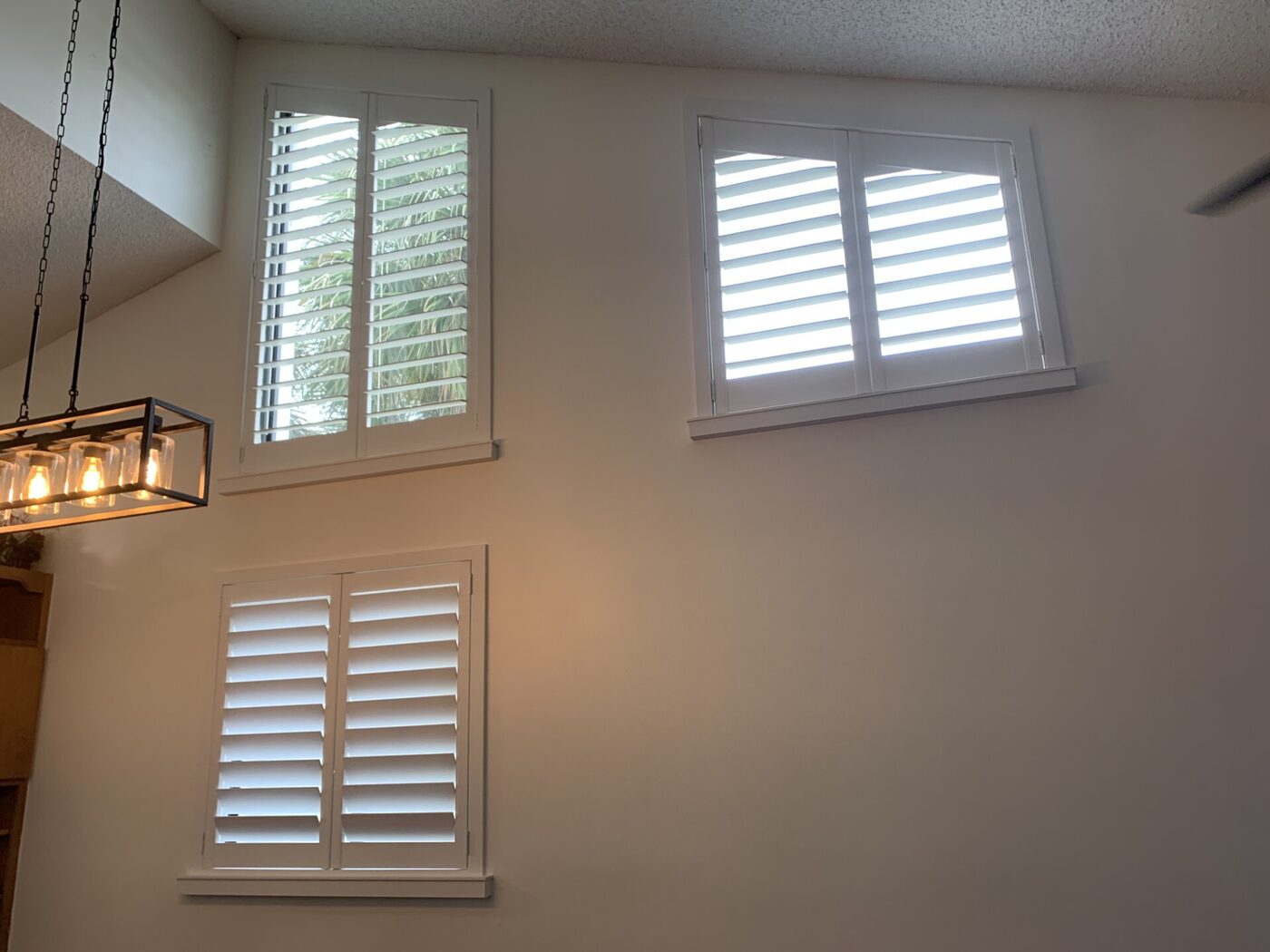 Real-wood plantation shutters on vaulted specialty-shape windows in a Palm City, FL luxury living room