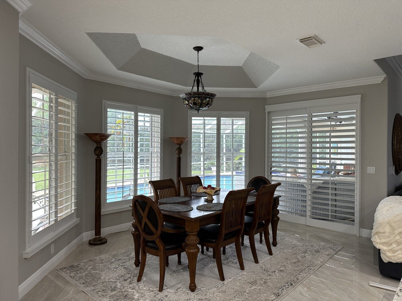 Dining room plantation shutters with pool view