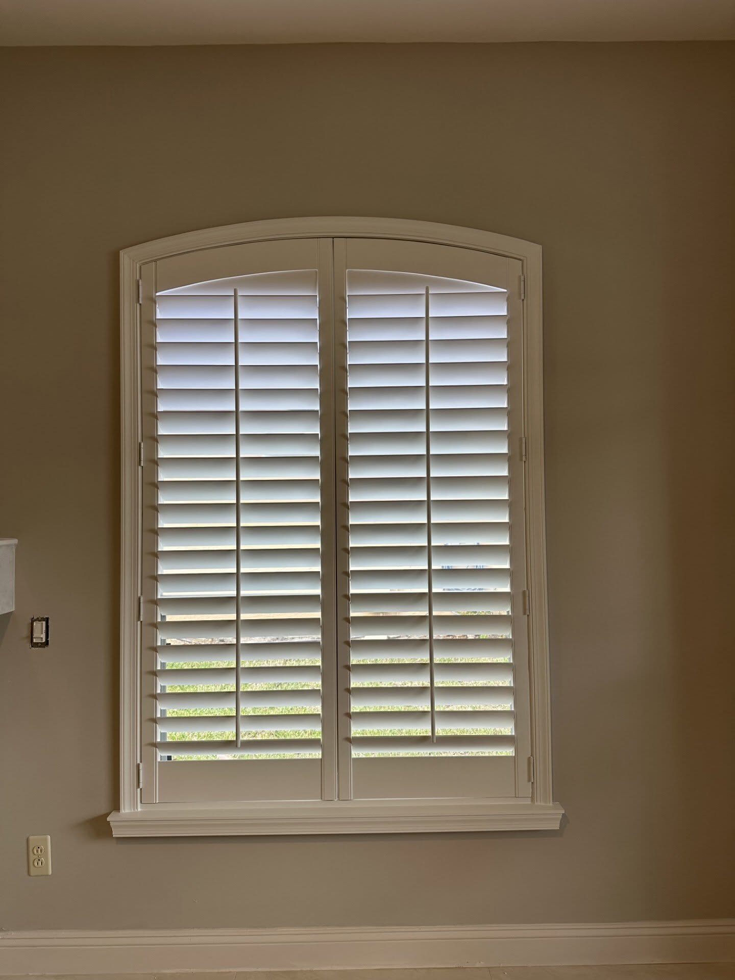 Arched custom wood plantation shutters fitted to the same window after installation by Architectural Plantation Shutters