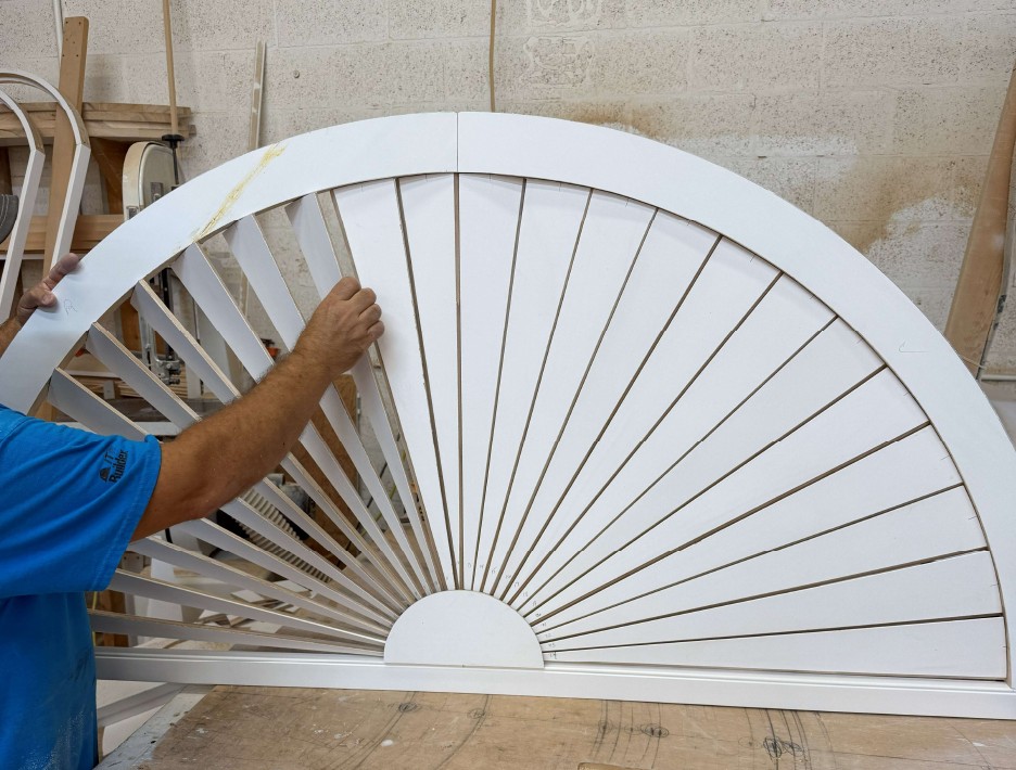 Craftsman checking adjustable louvers on an assembled half-round sunburst plantation shutter