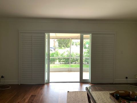 White shutter faces gathered at both ends with the central glass doorway exposed