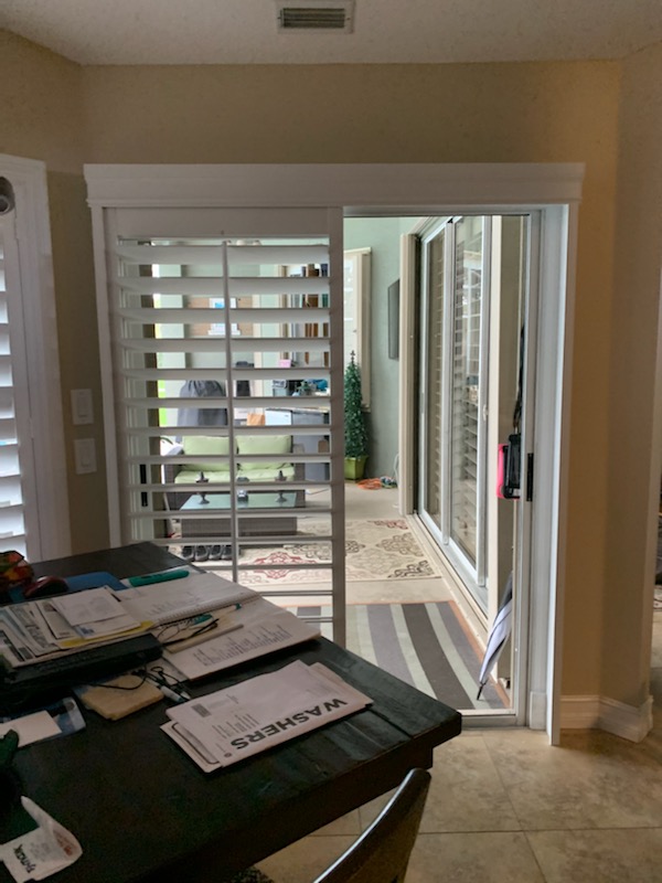 White shutter face gathered left beside an exposed patio doorway in a dining area