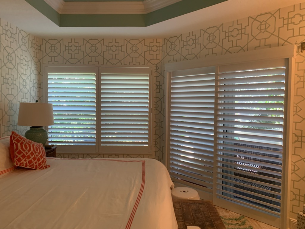 White shutter panels across a bedroom glass door beside matching window shutters