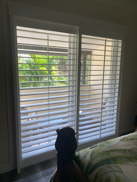 Two white shutter faces with open louvers across a bedroom balcony door