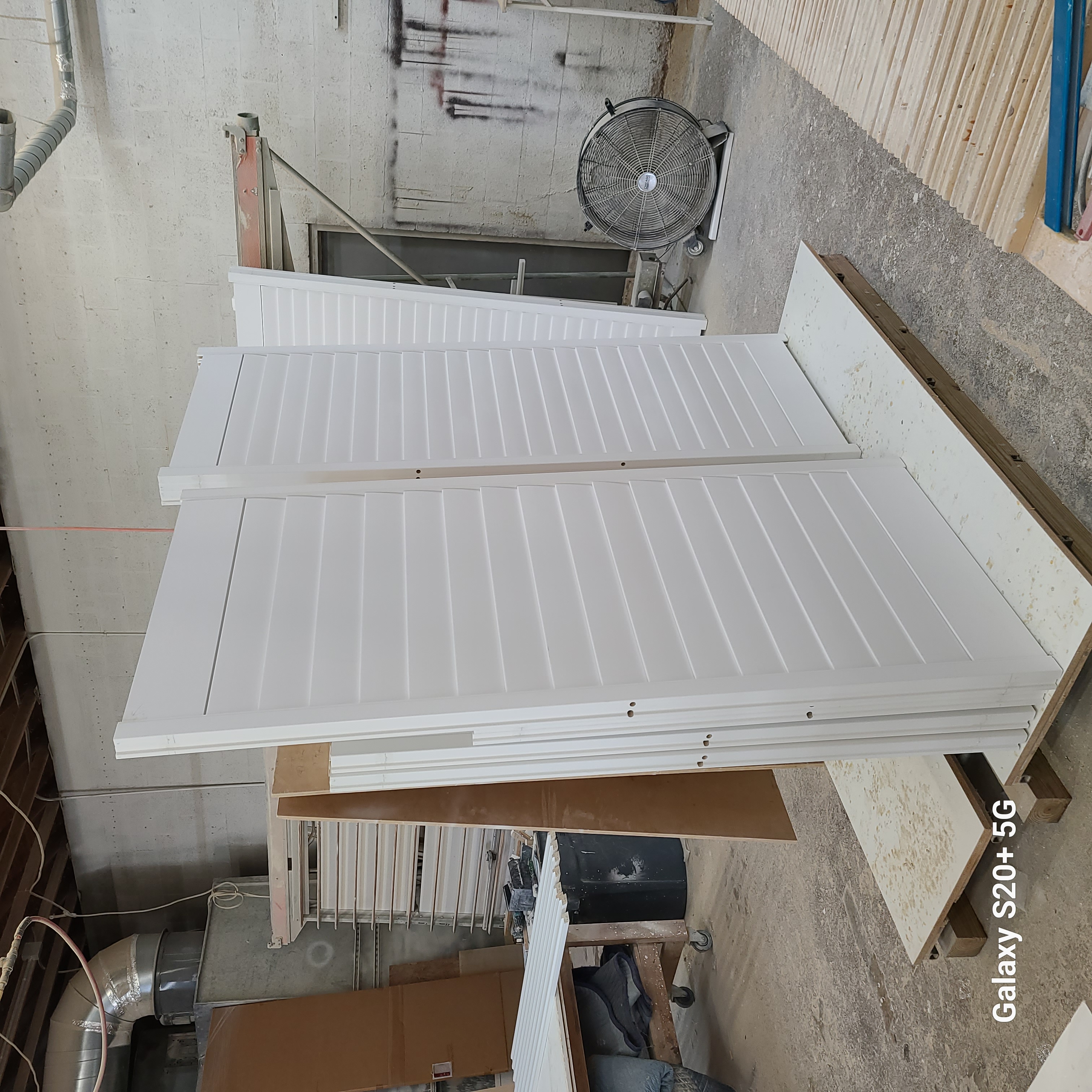 Assembled white shutter panels standing together on a workshop bench