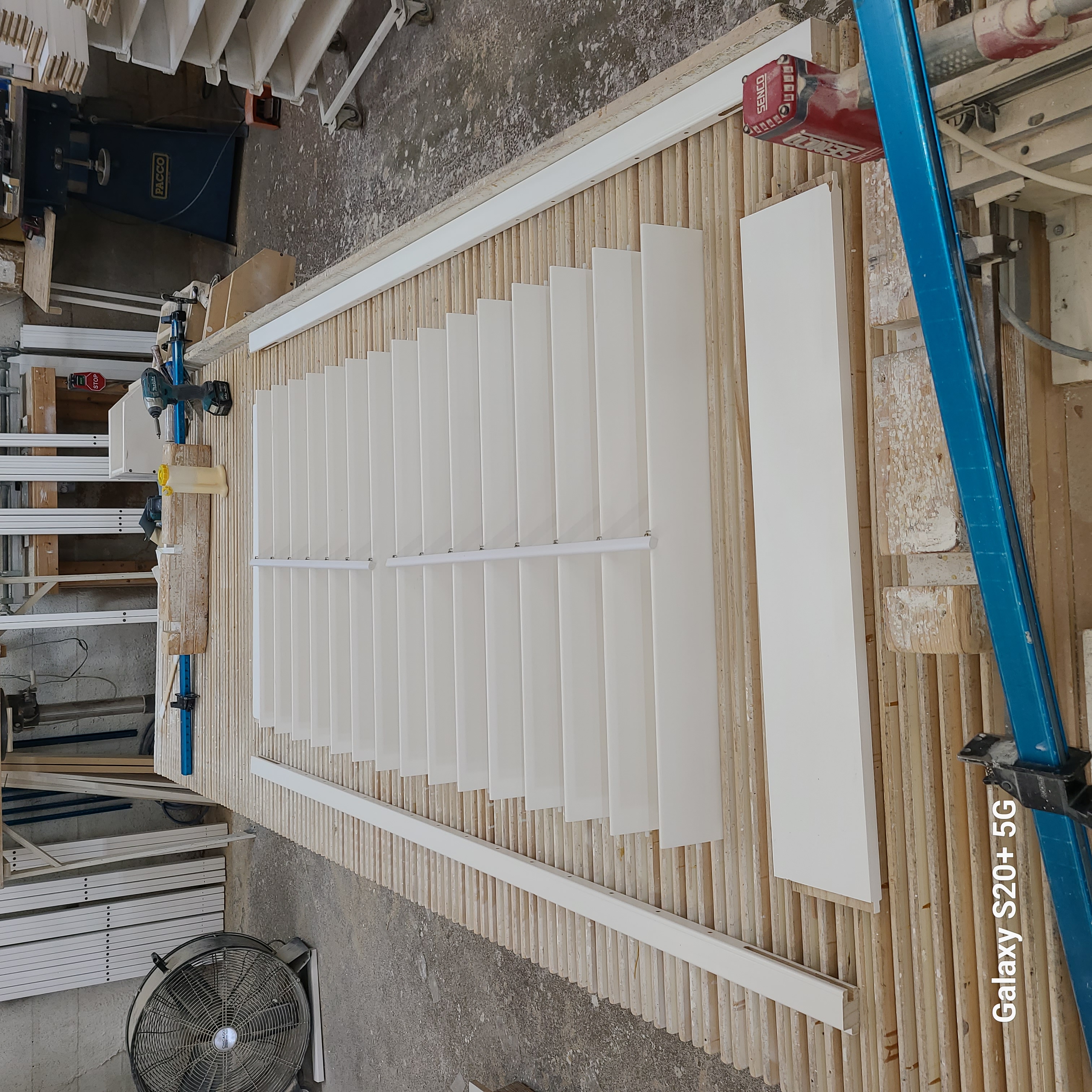 White louvers and surrounding shutter components laid out on a workbench