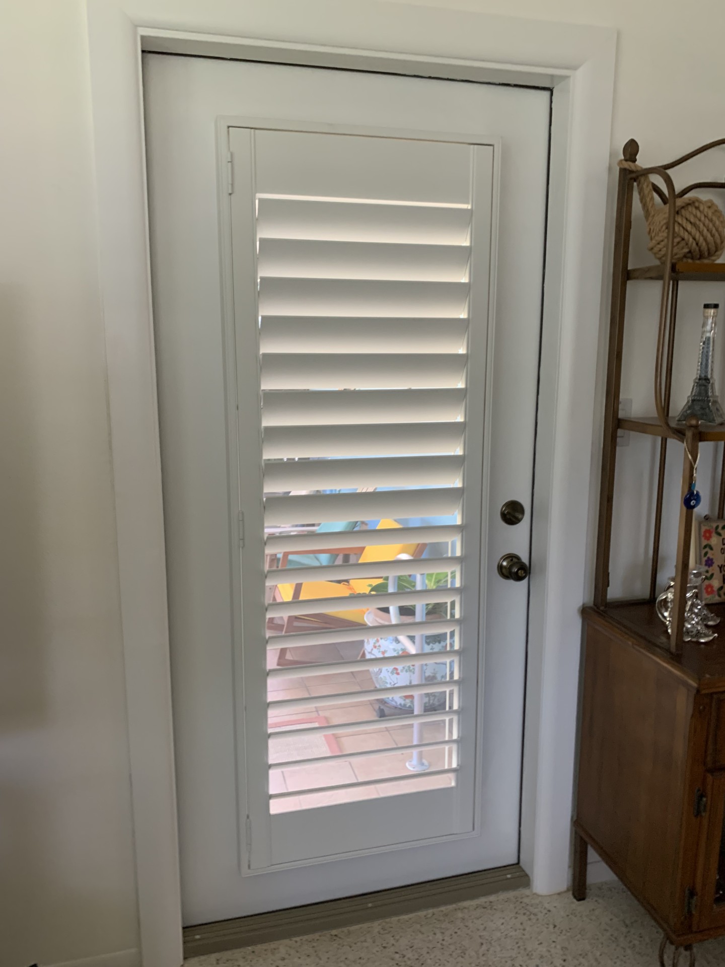 White shutter on a single glass door with a straight frame beside the knob and deadbolt