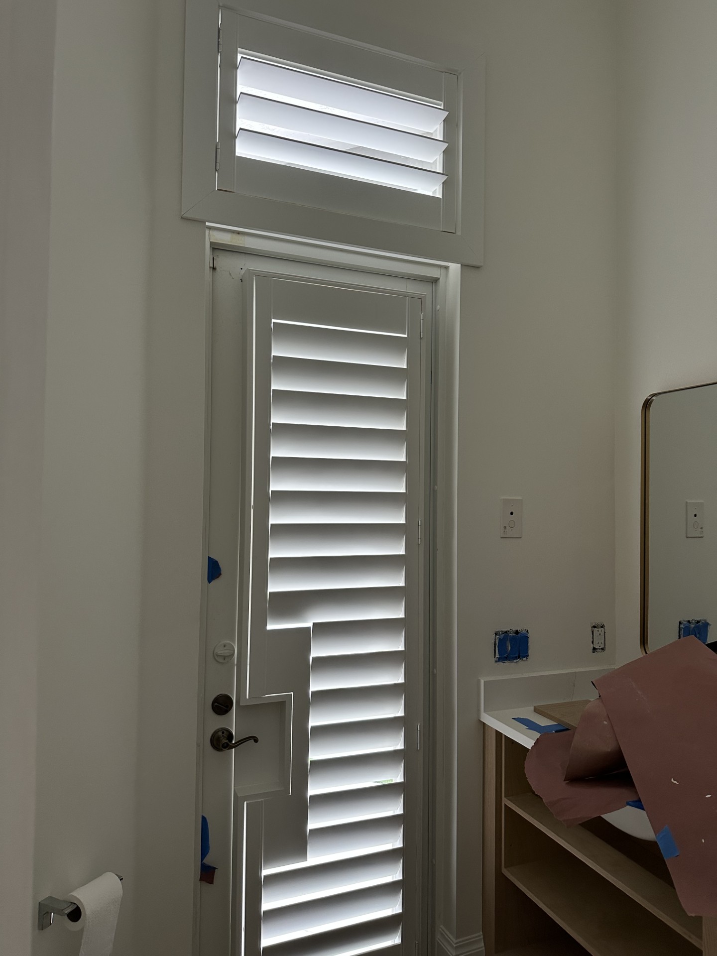 White glass-door shutter with a rectangular handle cutout and a matching shutter in the transom above