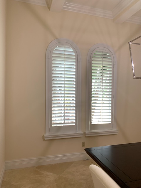Two narrow round-top windows with individual white louvered shutter panels