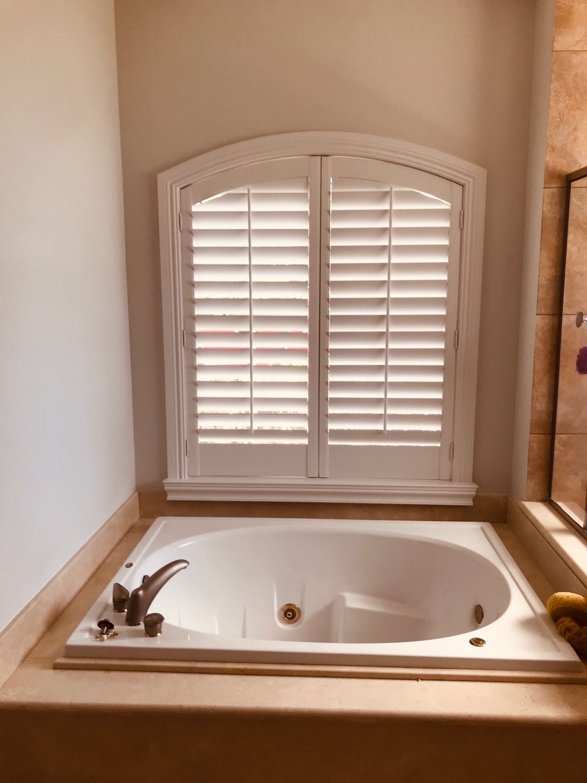 Two custom segmented arch shutter panels above a bathtub