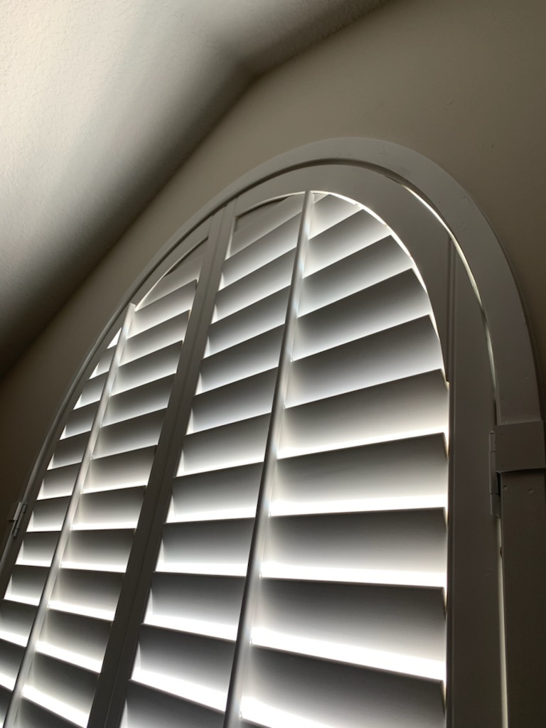 Close-up of horizontal shutter louvers and curved top rails at an arch
