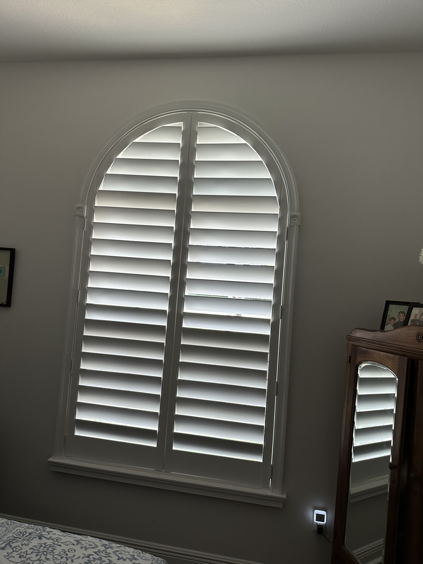 White full-height arched shutters with horizontal louvers in a curved frame