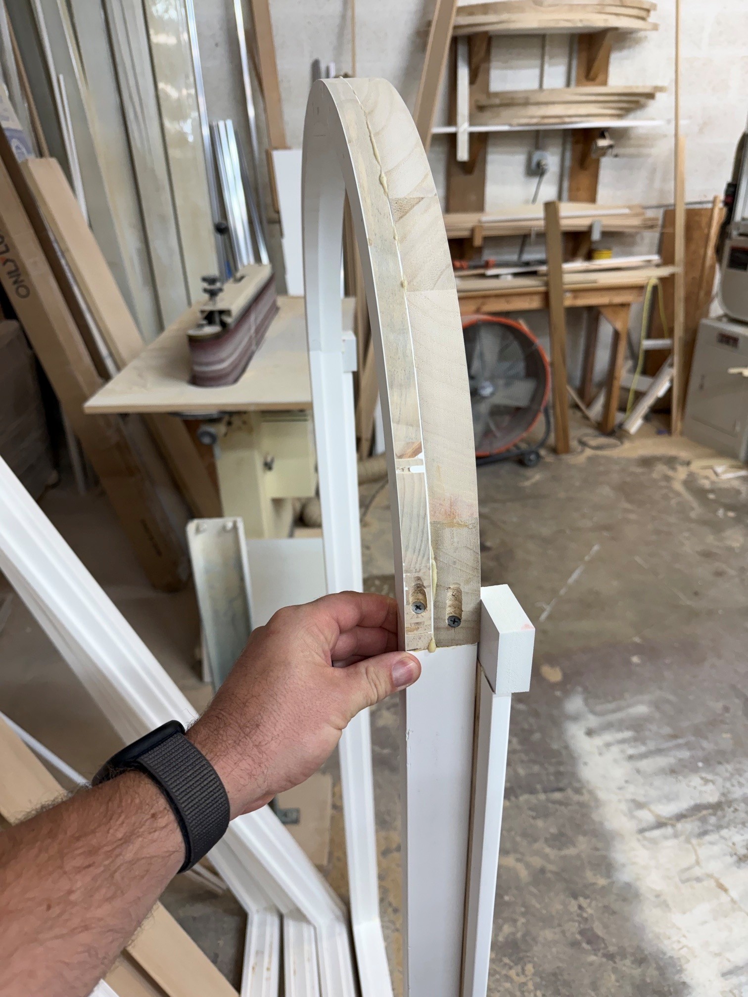 Rear view of a curved wood shutter frame with visible joints and recessed fasteners