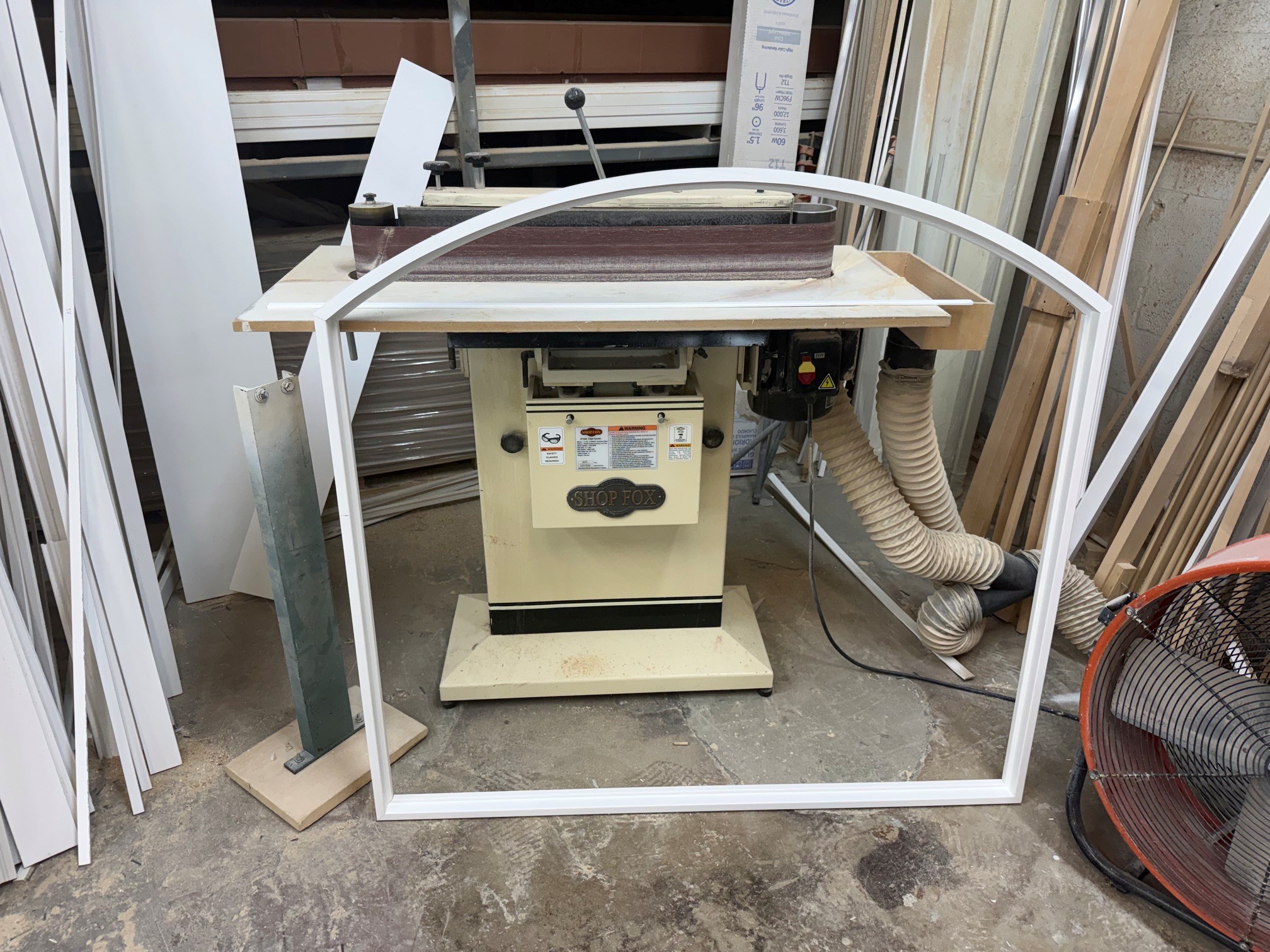 Shallow arched shutter frame beside an edge sander in the AP Shutters workshop