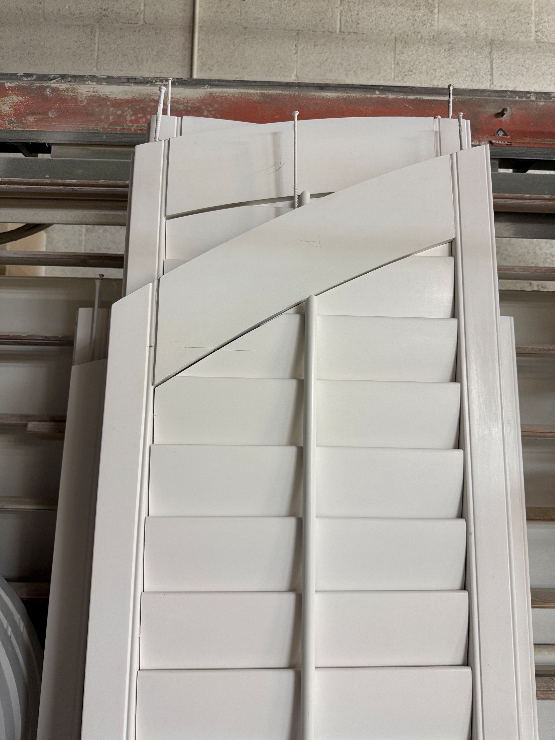 Shaped shutter panels with horizontal louvers and center tilt rods on a shop rack