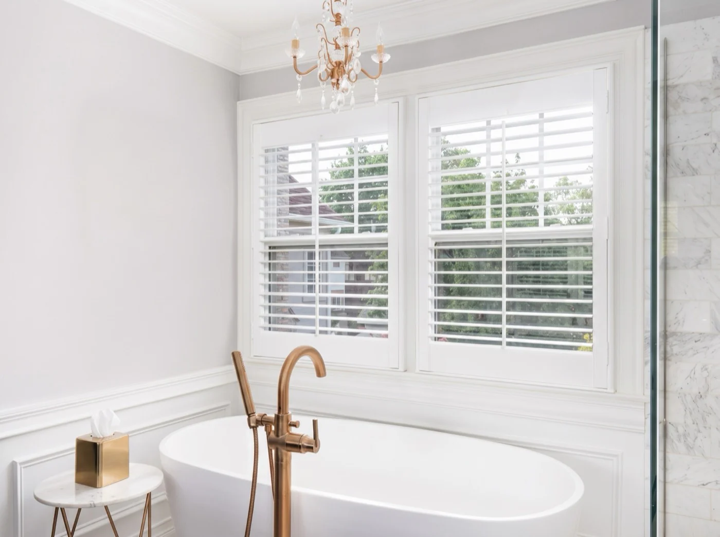 White plantation shutters fitted around a bathtub