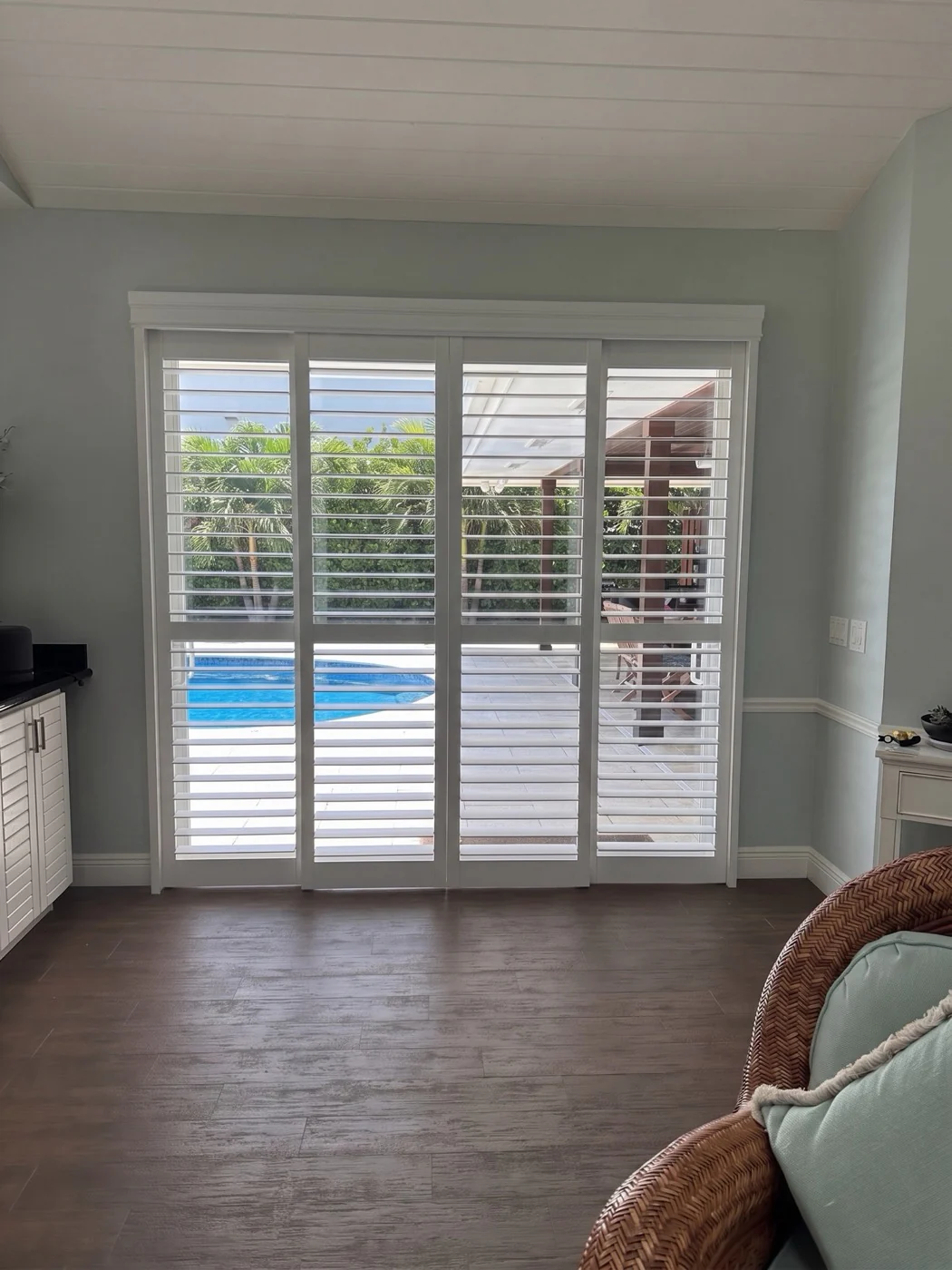 White bypass plantation shutters at a wide sliding glass door