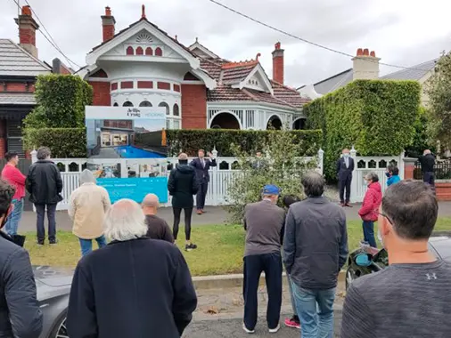 A crowd watching a property auction in Albert Park