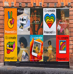 Colorful Polaroid advertisement posters featuring peace signs, rainbow hearts, vintage cameras, and diverse people holding Polaroid photos against a brick wall.