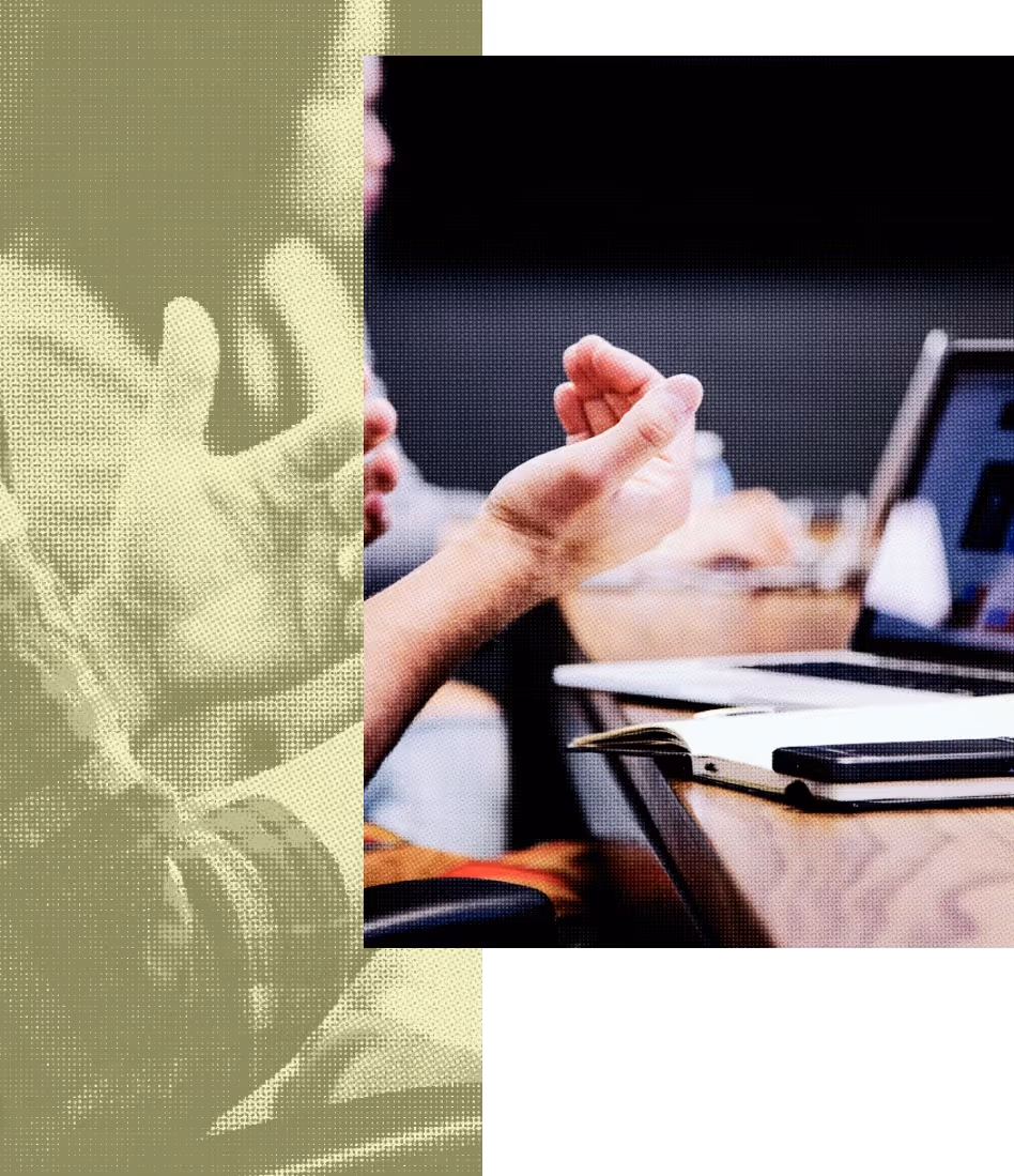 Person's hands gesturing above a desk with an open laptop and notebook.
